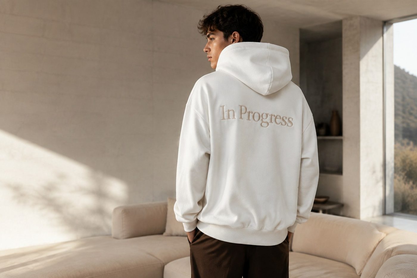 Back view of the In Progress hoodie in a quiet, sunlit room