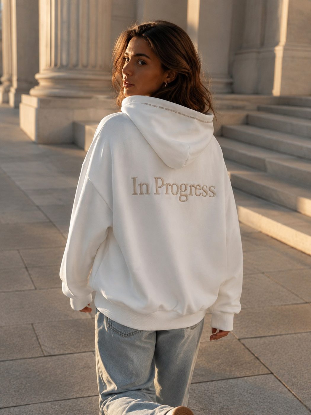 Person walking away in the In Progress hoodie, glancing back